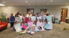 Twenty-one experienced- and beginner-student sewers, including co-leader Dorcas Sweeny (left), display some of the 120 pillowcases they donated to a local nursing home.
